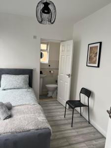 a bedroom with a bed and a chair and a bathroom at Cheerful 5 Bedrooms & En-Suite Bathrooms Town House in Northampton