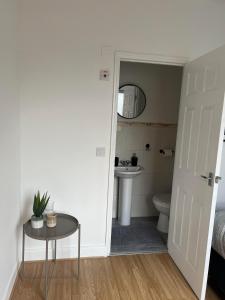 a bathroom with a sink and a toilet and a table at Cheerful 5 Bedrooms & En-Suite Bathrooms Town House in Northampton