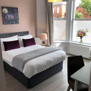 a bedroom with a large bed and two windows at The Muse - Luxury 5 Bedroom House in Belfast