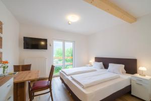 a bedroom with a large white bed and a desk and a window at Wellness Landhaus Parth in Ossiach