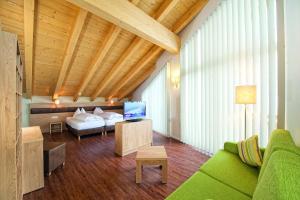a living room with a green couch and a bed at Hotel ALPINA in Saalbach-Hinterglemm