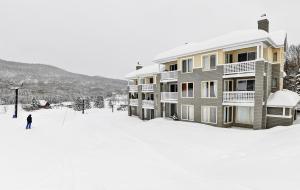 una persona parada en la nieve frente a un edificio en Hameau 24#22 - Studio en Stoneham