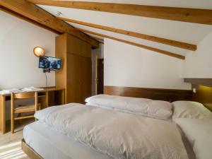 a bedroom with two beds and a tv on the wall at Hotel Ferrari in Pinzolo