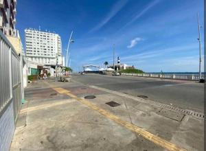 an empty street next to the ocean with a building at 1/4, sala, Farol da Barra. in Salvador