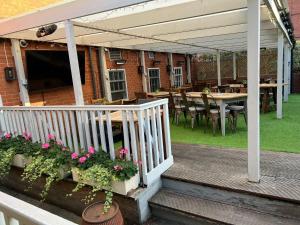 une terrasse couverte avec une table, des chaises et une balustrade blanche. dans l'établissement The Pig and Whistle, à Londres