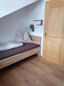 a bed in a room with a wooden door at Bichlerhof in Hopfgarten in Defereggen