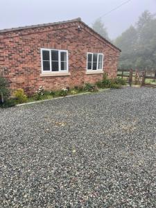a brick house with two windows on a gravel driveway at Apple Barn Guest House in Wisbech