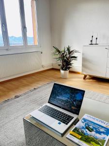 un ordenador portátil sentado en una mesa en una sala de estar en -The Urbanist- Lakeview Free Parking 2BD Fast WiFi, en Oberhofen am Thunersee