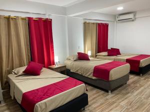 プロビデンシアにあるPOSADA VILLA BRYANの赤いカーテンが備わるドミトリールームのベッド2台分です。