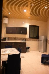 een keuken met een tafel en een koelkast bij بيوتات الزير in Al Baha