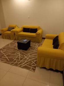 a living room with two yellow couches and a rug at بيوتات الزير in Al Baha