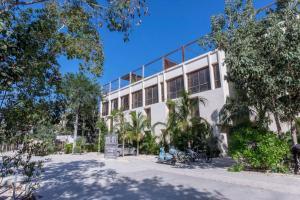 Un edificio blanco con árboles delante. en Exquisite Tulum jungle condo w/private pool!, en Tulum