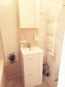 ein weißes Badezimmer mit einem Waschbecken und einem Spiegel in der Unterkunft Au PeTiT BoNhEuR Cauterets centre-ville in Cauterets