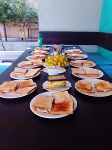 a long black table with plates of sandwiches and bananas at Hangover Hostels Mirissa in Mirissa