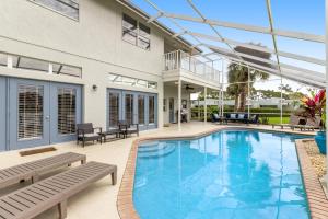 a swimming pool with benches and a house at Paradiso Probay in Bradenton