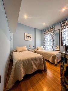 Habitación con 2 camas, paredes azules y suelo de madera. en VTAR Casa las Tinajas, en Baeza