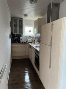 a kitchen with white cabinets and a refrigerator at Bungalow 33 in Tossens in Tossenserdeich