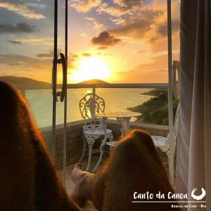 Dos personas sentadas en un balcón con vistas a la puesta de sol en Canto da Canoa, en Arraial do Cabo