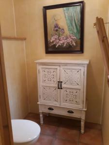 bagno con armadietto bianco e dipinto sul muro di Casa acogedora con barbacoa a Miravet Altre 61 foto