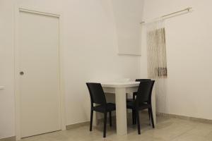 uma mesa branca com cadeiras pretas num quarto em B&b Bianco em Orta Nova