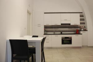uma cozinha com armários brancos e uma mesa e cadeiras em B&b Bianco em Orta Nova