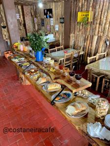a long table with plates of food on it at Vila Ecológica Pousada Holística in Cambara do Sul