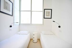 Cette chambre blanche dispose de 2 lits et d'une fenêtre. dans l'établissement Classic Malte by HolyGuest, à Tel Aviv