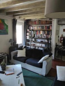 uma sala de estar com um sofá e uma estante de livros com livros em Agréable chambre d'hôte 