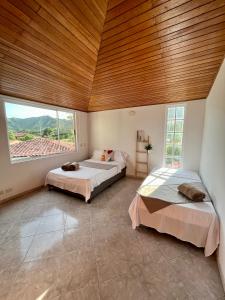 two beds in a room with a wooden ceiling at Finca tres colinas in Lemos