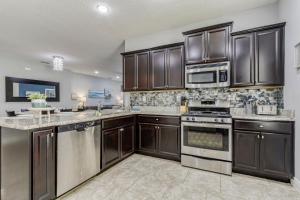 a kitchen with stainless steel appliances and brown cabinets at Oasis at Solterra - 5 bed family resort pool home in Davenport