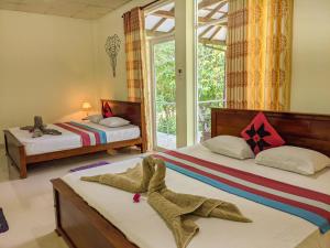 1 dormitorio con 2 camas y ventana en Choona Lodge 'view of sigiriya & pidurangala with sunrise', en Sigiriya
