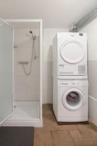 uma máquina de lavar roupa na casa de banho com um chuveiro em court séjour em Houssen