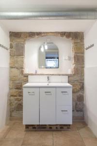 ein weißes Badezimmer mit einem Waschbecken und einem Spiegel in der Unterkunft court séjour in Houssen