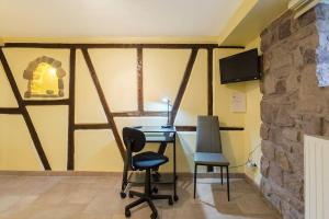 a desk and two chairs in a room with a stone wall at court séjour in Houssen