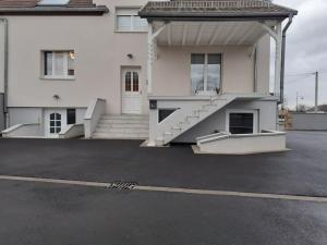 een wit huis met trappen op een parkeerplaats bij court séjour in Houssen