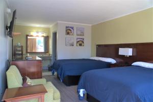 a hotel room with two beds and a chair at Eastern Shore Motel in Daphne