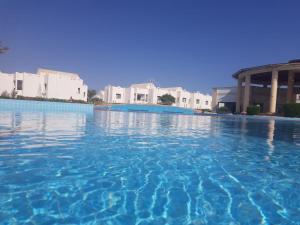 Diar El Rabwa Modern Apartment في شرم الشيخ: مسبح بمياه زرقاء امام مباني بيضاء