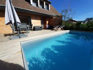a swimming pool with an umbrella and a table and chairs at Villa Jules Grand Gîte in Agon Coutainville