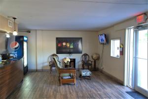 een woonkamer met stoelen en een tafel en een televisie bij Eastern Shore Motel in Daphne