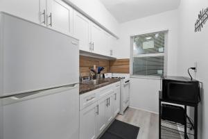 マイアミにあるBeautiful 1 Bedroom Apartment In Miamiの白いキャビネット、シンク、テレビ付きのキッチン