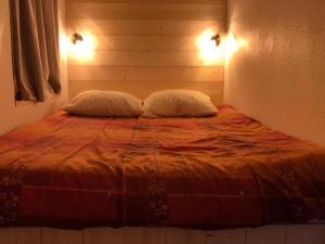 ein Bett mit zwei Kissen darauf in einem Schlafzimmer in der Unterkunft Appartement résidence L'Ours blanc chez Jimmy in Huez