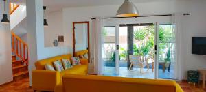 a living room with a yellow couch and a sliding glass door at Villa Fedelian 2 Playa Blanca in Playa Blanca