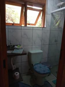 uma casa de banho com um WC e uma janela em Chalé Da Bia em Cananeia