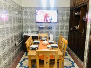 une table à manger avec des chaises et une télévision murale dans l'établissement Dream Salé, à Sale
