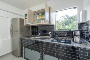 a black tiled kitchen with a sink and a refrigerator at Casa c Wi-Fi e otima localizacao - Testo Salto SC in Blumenau