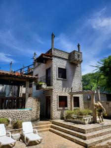 une maison en pierre avec des chaises devant elle dans l'établissement Hostal casa de las gargolas, à Amapala