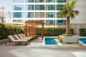 un patio con sillas y una piscina frente a un edificio en Sonder Business Bay, en Dubái