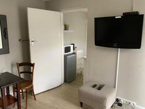 a living room with a television on a wall with a chair at La Roche Stay in Port Elizabeth