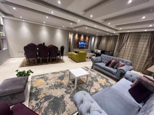 Cozy and Modern Apartment for Rent in Mohandessin في القاهرة: غرفة معيشة مع كنب وطاولة وكراسي