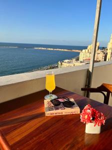 Hyde Park House Hotel في الإسكندرية: كوب عصير برتقال وكتاب على طاولة